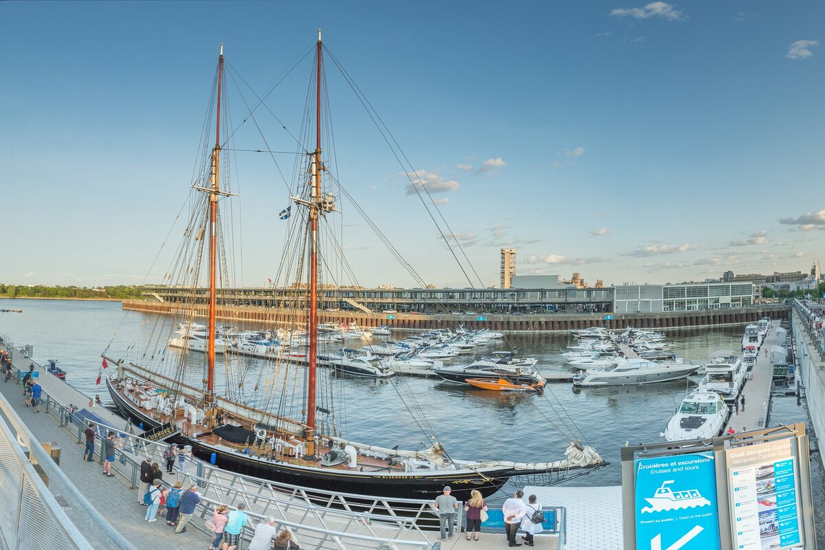 The Old Port of Montreal on a summer evening, with a tall ship moored beside a marina full of boats
