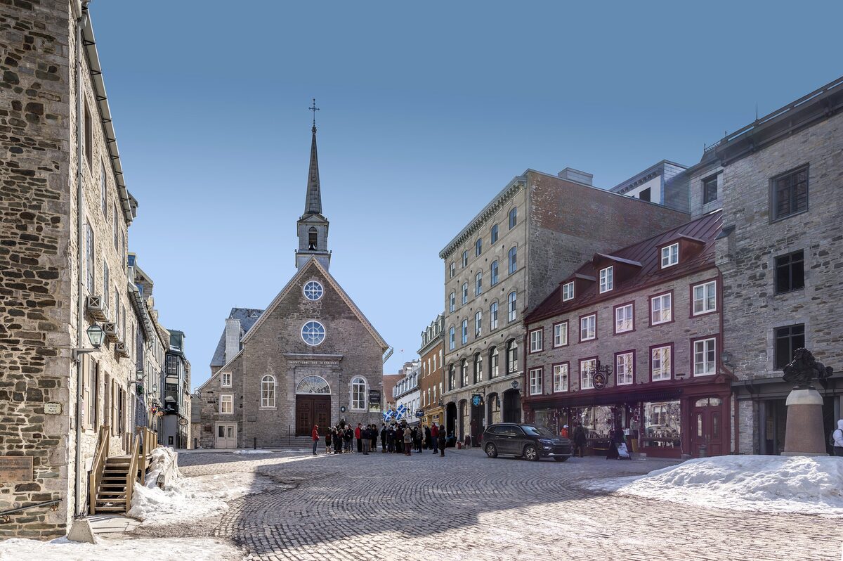 The stone church of Notre-Dame-des-Victoires on Place Royale, with snow banked along the cobbled square