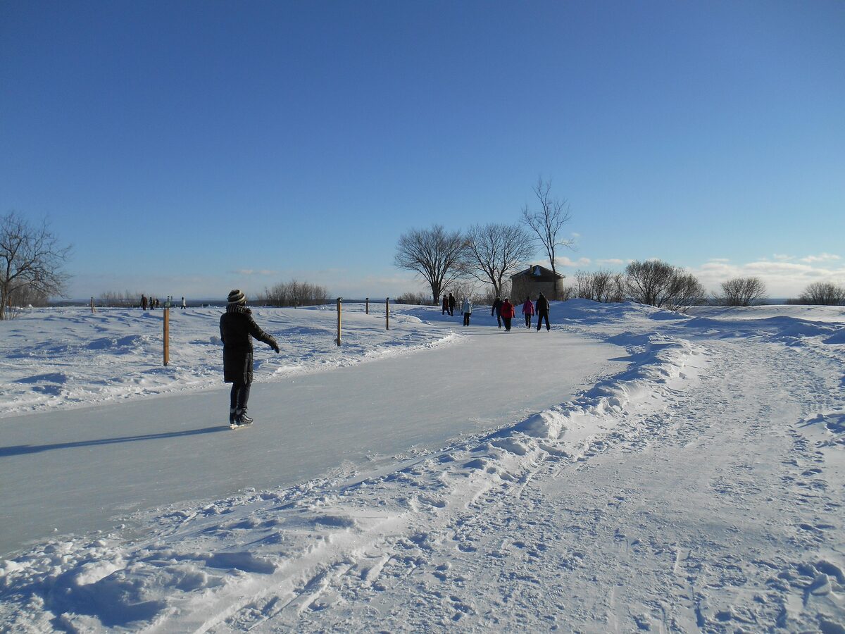 A skater on a groomed ice trail across the snow-covered Plains of Abraham on a clear winter day