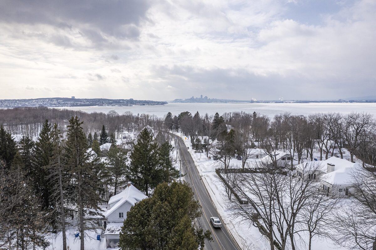 Chemin Royal in Sainte-Pétronille under snow, with the St. Lawrence River and Quebec City on the horizon