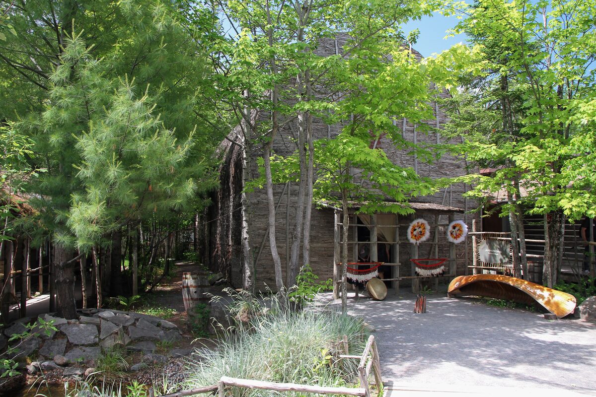 A Huron-Wendat longhouse of bark and timber among trees at the traditional site in Wendake