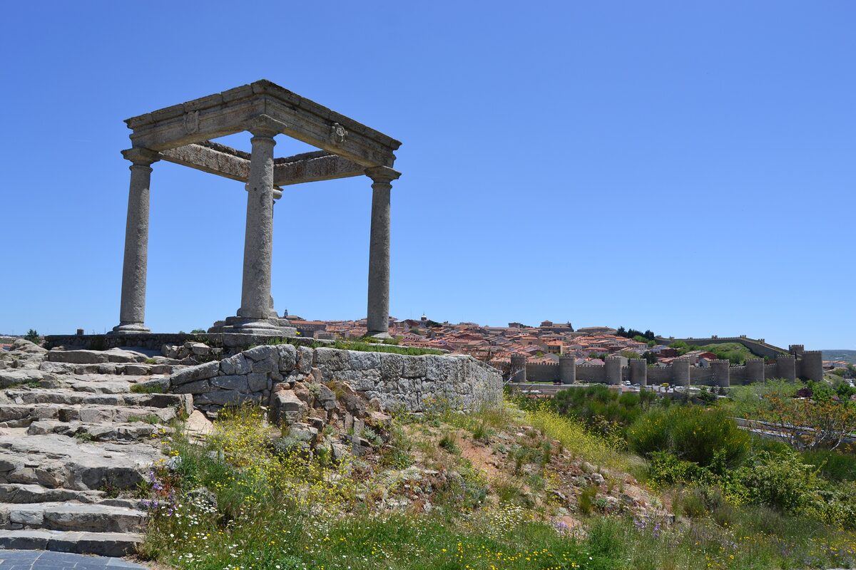 The four stone columns of Los Cuatro Postes on a rocky hilltop, with the city beyond