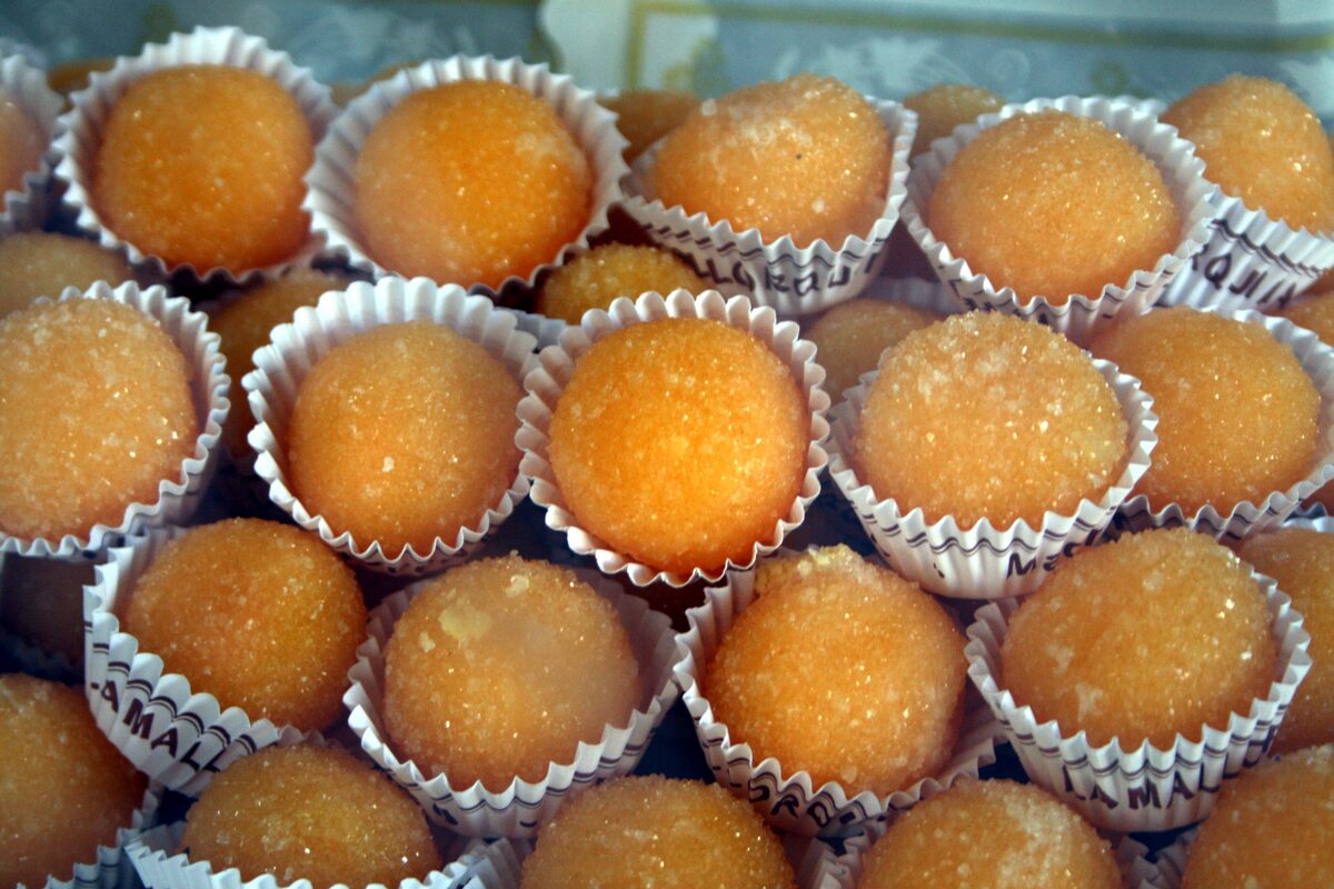Rows of round, sugar-dusted egg-yolk sweets in white paper cups
