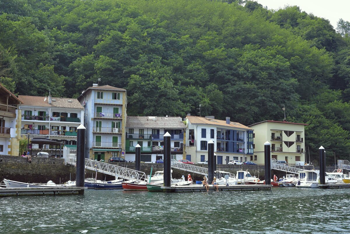 Pasai San Pedro: pastel houses on the waterfront above the harbor, with fishing boats moored in front and wooded hills behind