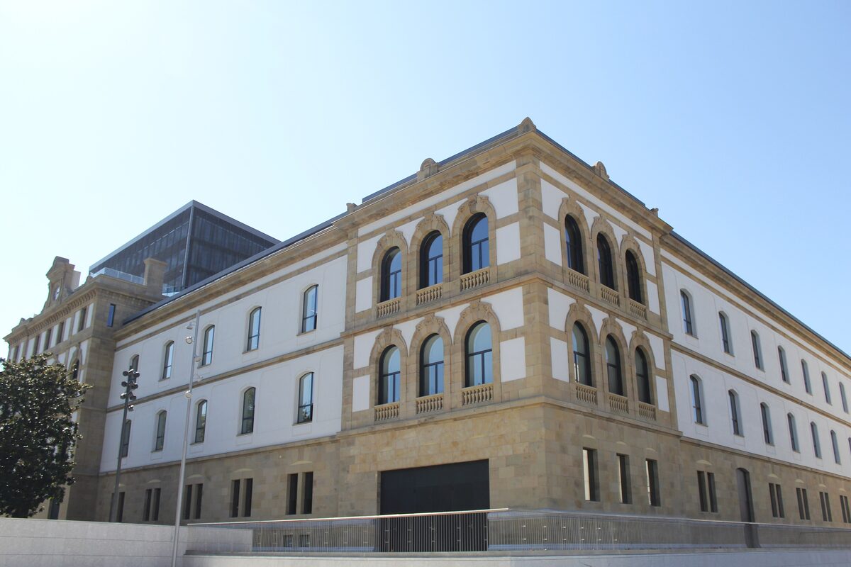 The long cream stone facade of Tabakalera, with rows of tall windows and a wide pavement in front