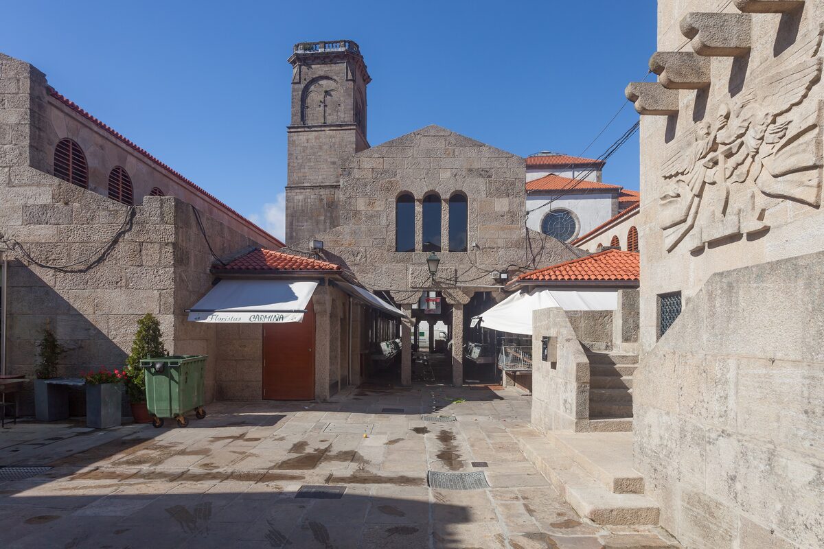 The courtyard of the Mercado de Abastos, with its tower, arched windows and a stone relief on the right