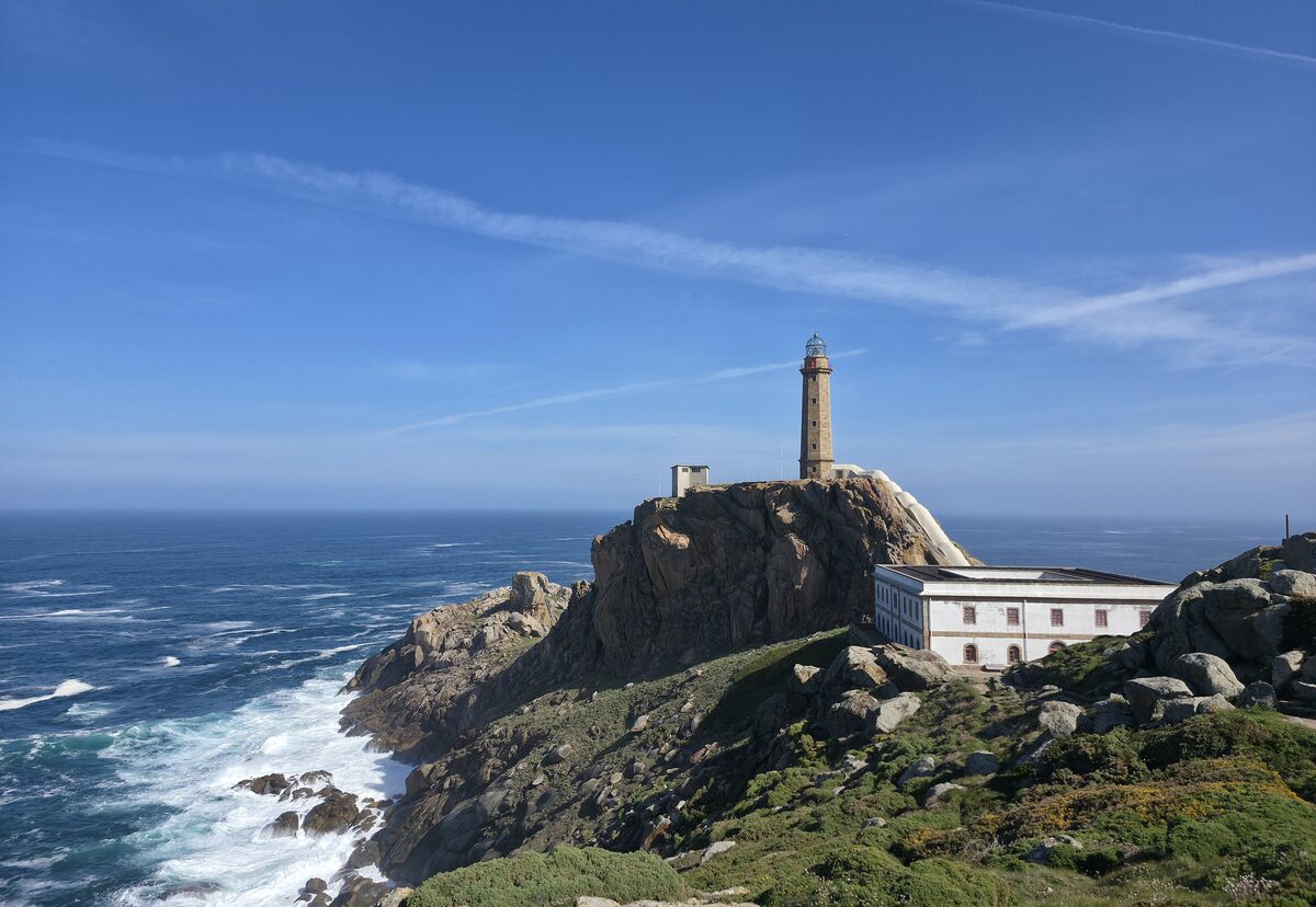 The Cabo Vilán lighthouse on its rocks above the sea, with the white keeper's house beside it