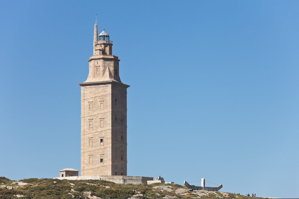 The Tower of Hercules on its grassy hilltop under a clear blue sky