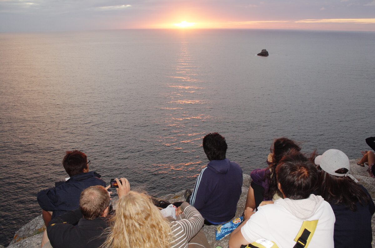 Visitors on the rocks at Fisterra watching the sun go down over the open Atlantic