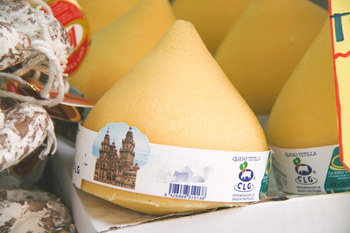 Cone-shaped Tetilla cheeses at a market stall, one in a box with a label showing the cathedral
