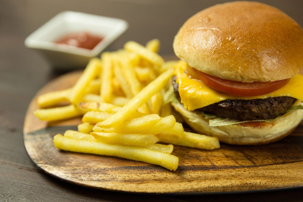 Cheeseburger with tomato and fries on a wooden board