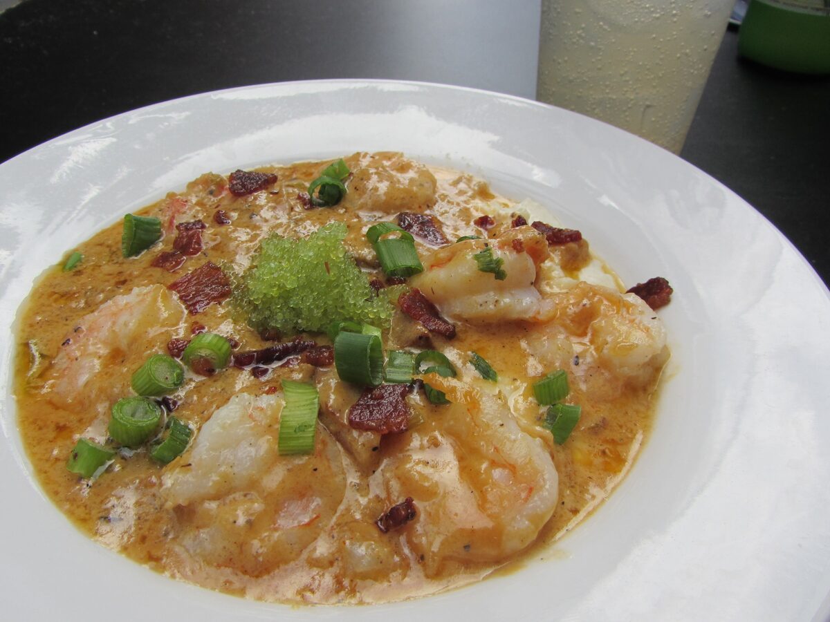 Shrimp and grits with bacon and scallions in a white bowl