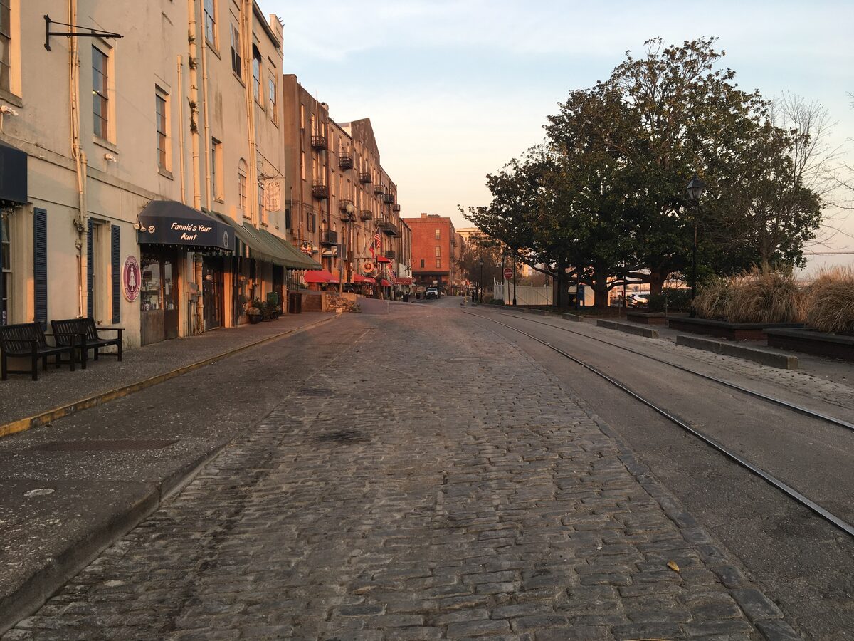 Quiet cobbled River Street at dusk with old brick warehouses