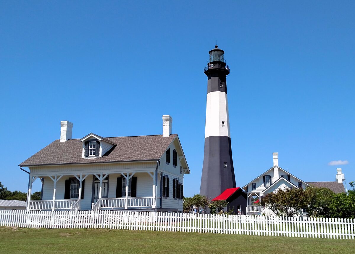 Black and white Tybee Island lighthouse beside the keeper's cottage