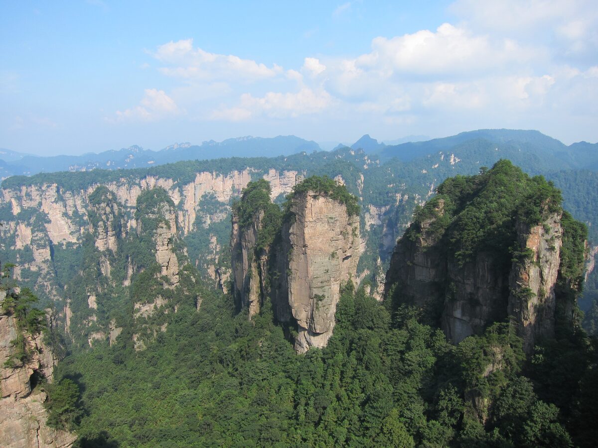 Sandstone pillars and ridges seen from the Huangshizhai viewpoint under a blue sky with clouds