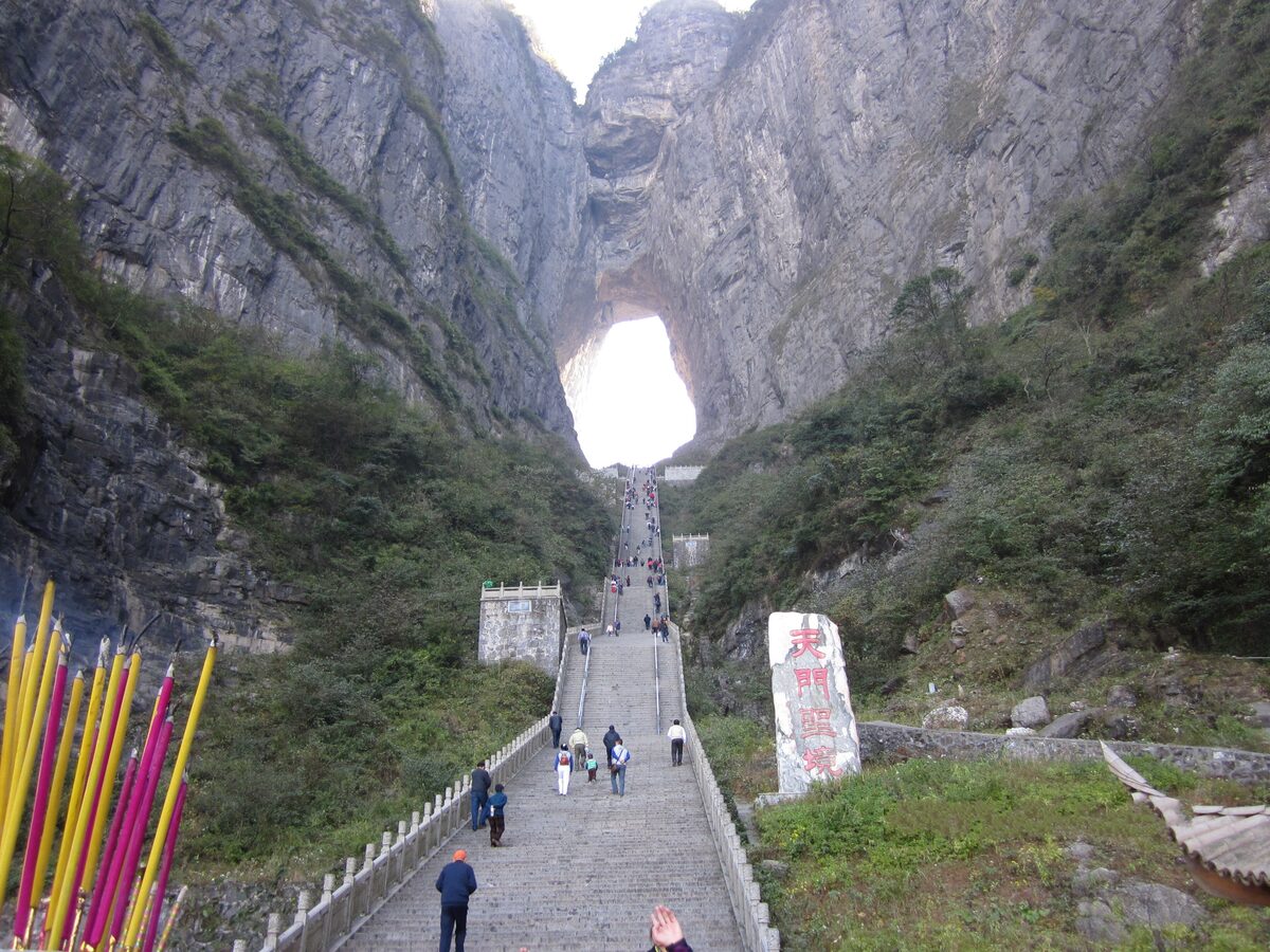 The long stone staircase climbing to Tianmen Cave, a huge natural arch in the cliff with bright sky showing through