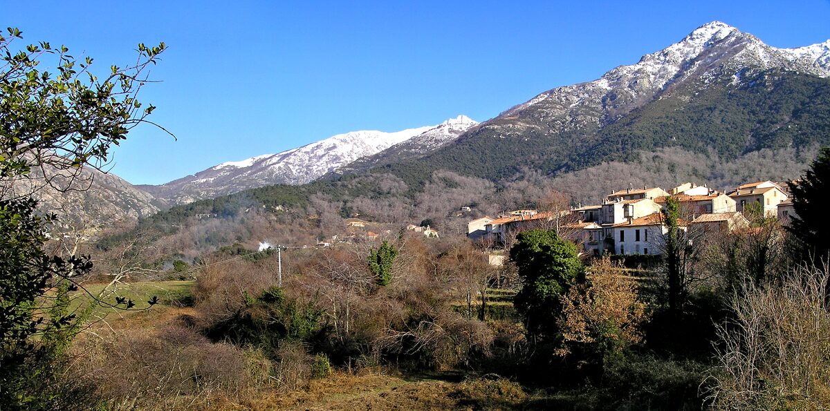 The village of Bocognano on the hillside, with snow on the mountain peaks above