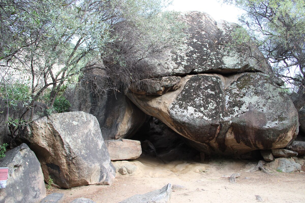 Huge granite boulders and a rock shelter at the Grotte Napoléon, shaded by trees