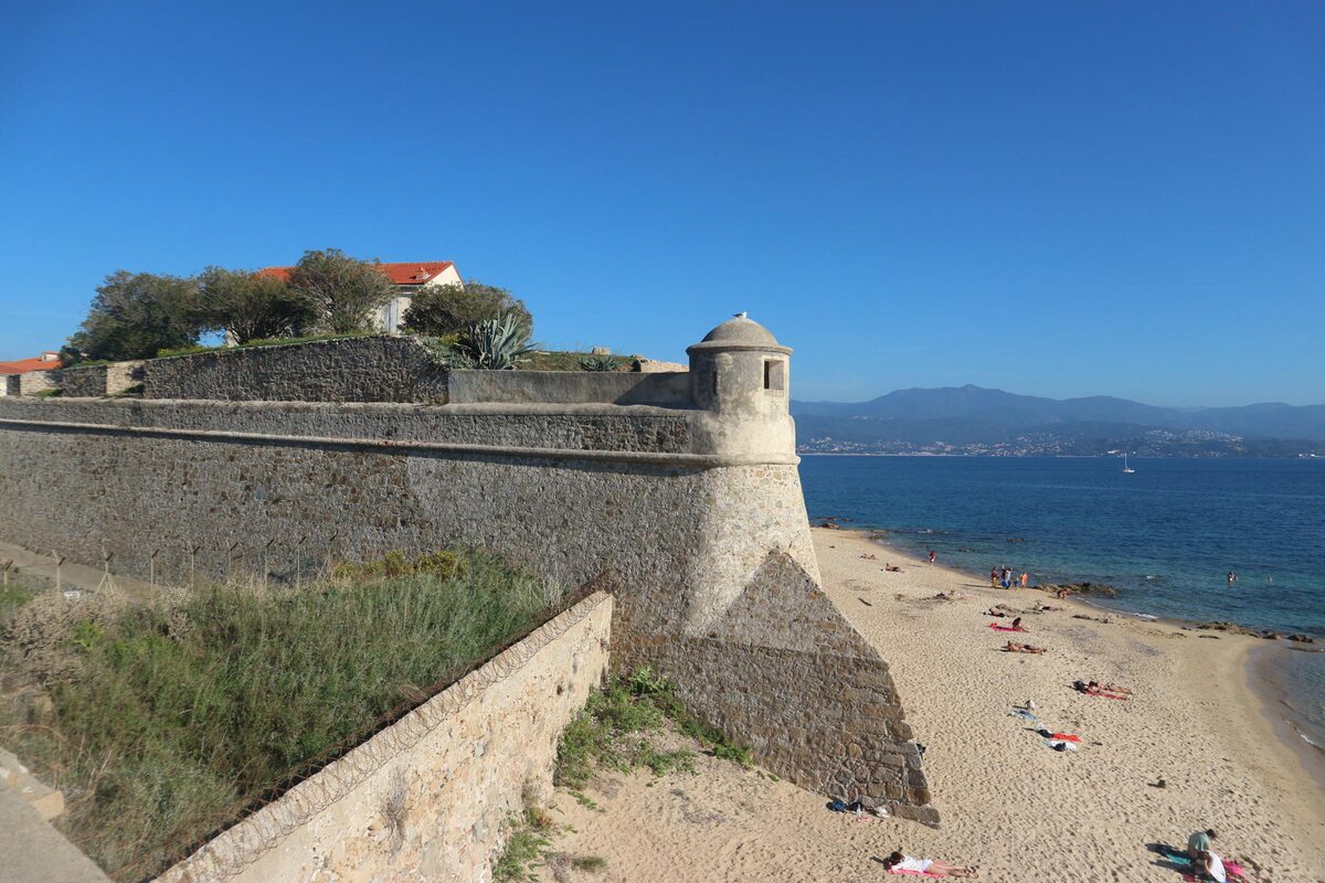 Saint-François, the town beach at the foot of the citadel bastion, with a stone corner turret, pale sand, a few sunbathers and the gulf beyond (Trottel lies further along the bay)