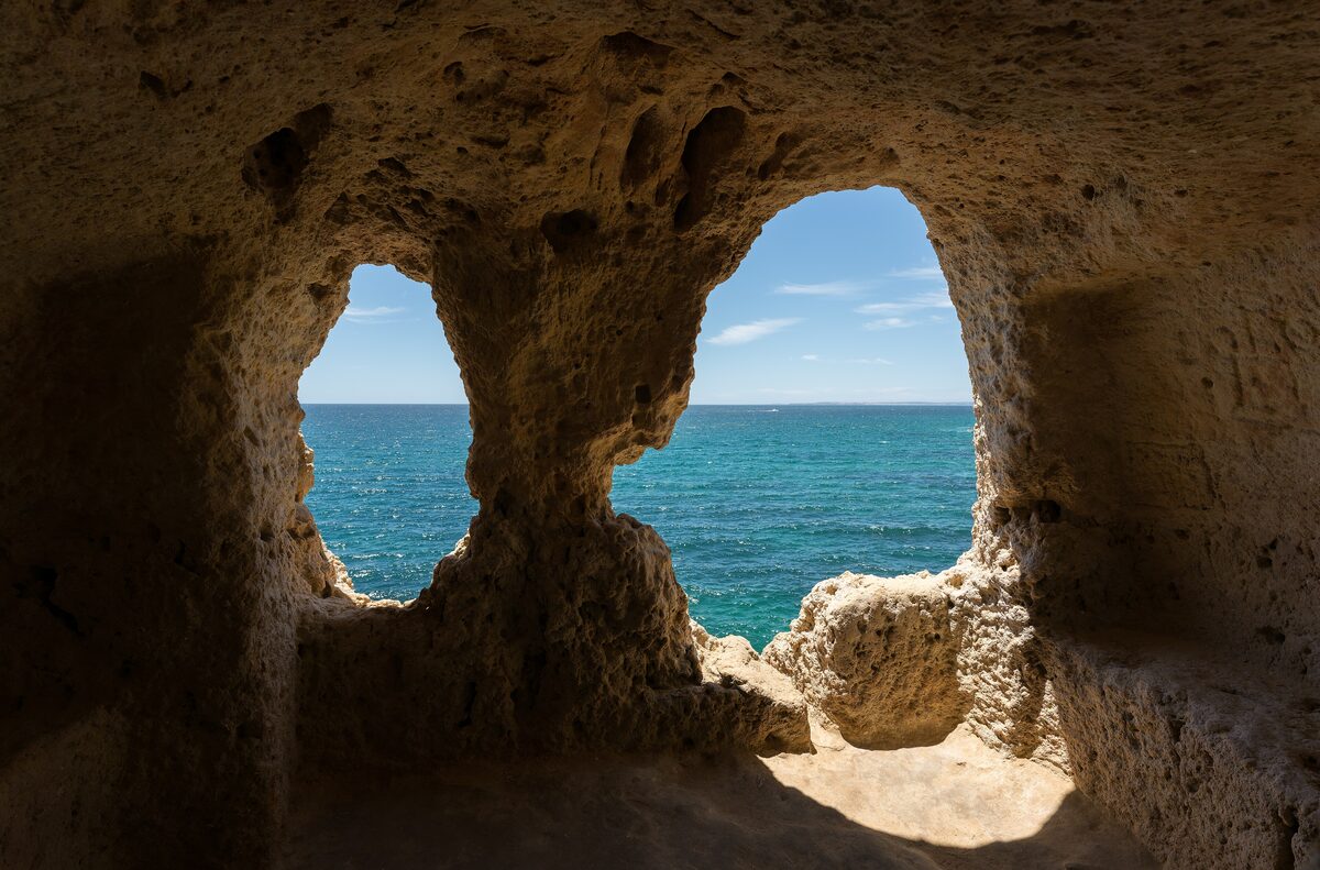Sea-carved rock window at Algar Seco with blue water beyond