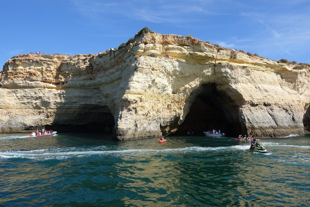 The mouth of the Benagil cave, with boats and kayaks in the water below the cliffs