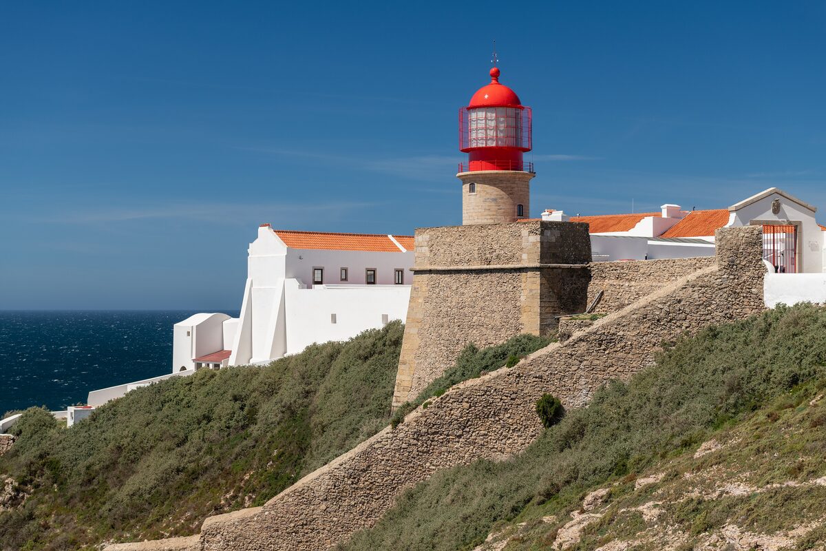 Red-topped lighthouse and fort walls on the cliffs at Cabo de São Vicente