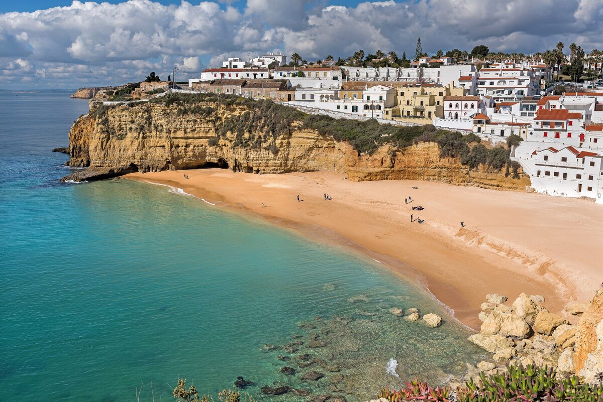 Carvoeiro beach with white village houses on the cliff above turquoise water