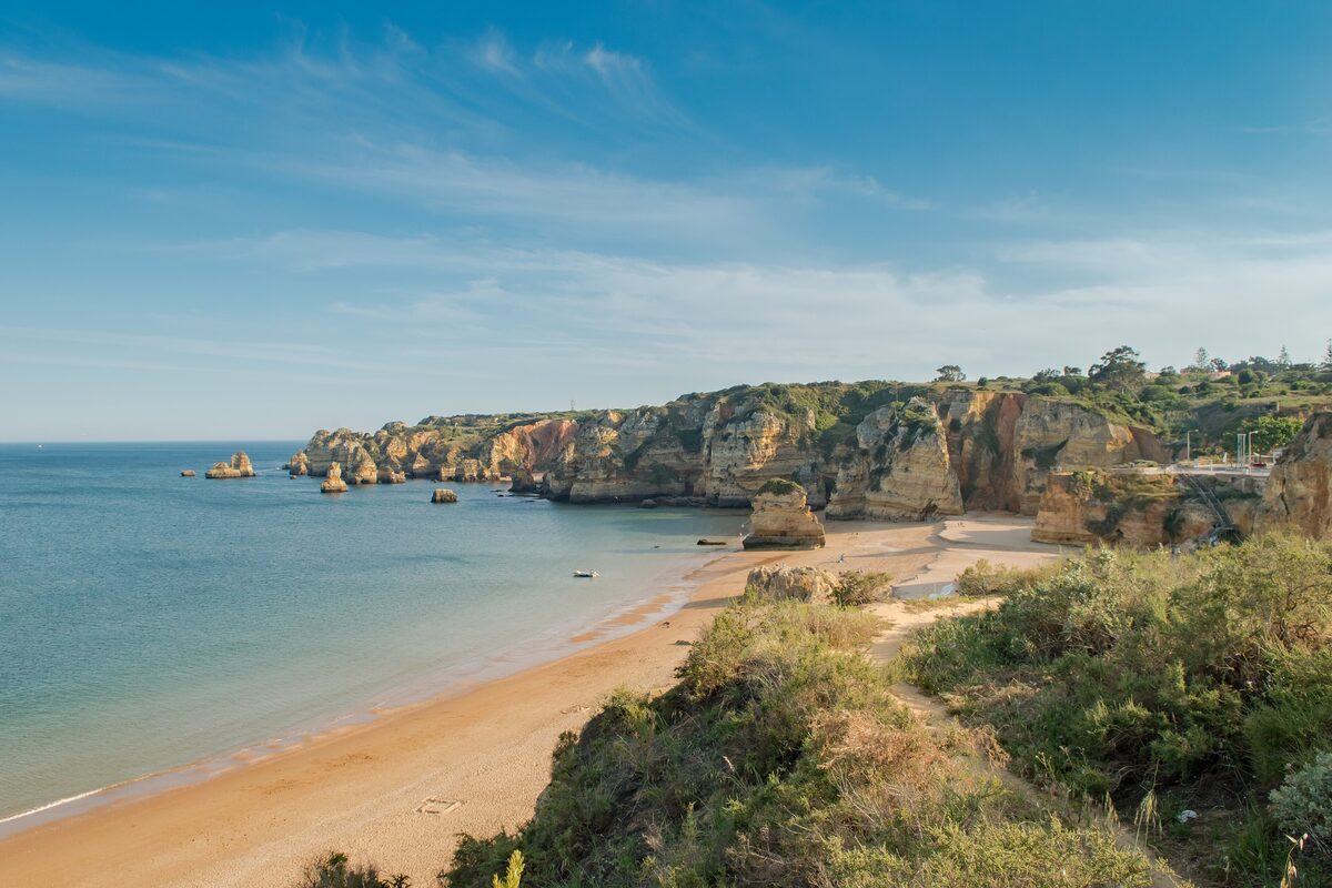 Praia da Dona Ana, a sandy beach below golden cliffs and sea stacks
