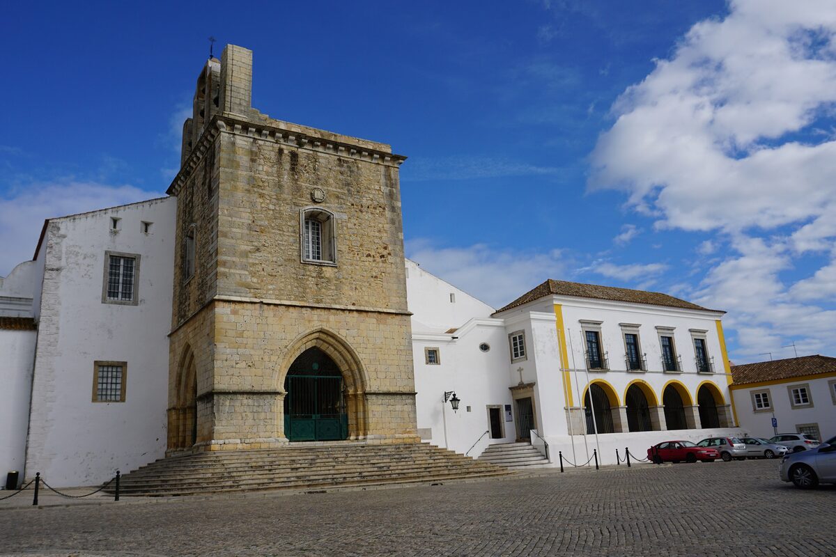 The cathedral of Faro with its tower and white buildings under blue sky
