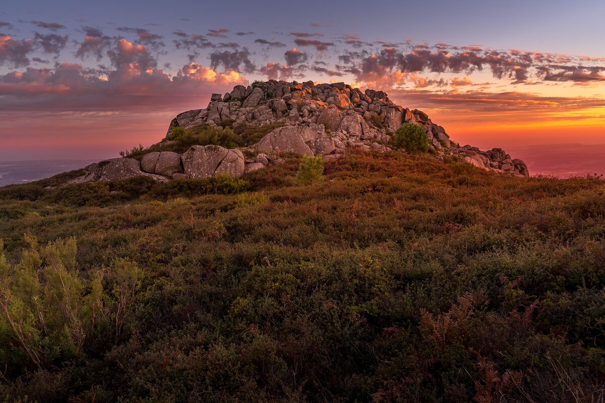 Granite boulders on the Fóia ridge at sunset, with heather around them