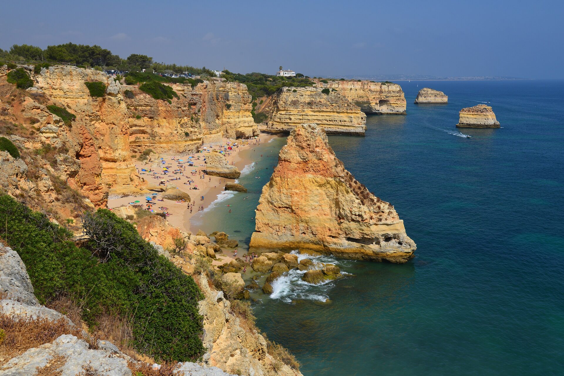 Golden cliffs, sea stacks and a sandy cove full of sunbathers at Praia da Marinha on the Algarve