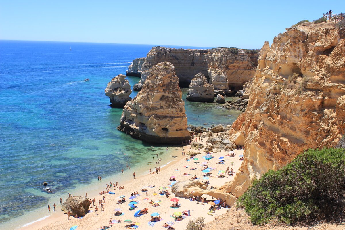 Praia da Marinha, a sandy cove full of sunbathers between golden cliffs