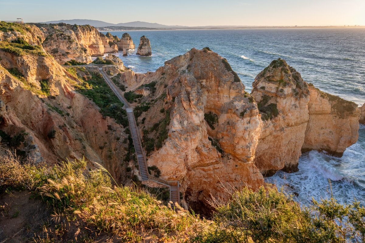 Golden cliffs and sea stacks of Ponta da Piedade with a wooden stairway down the headland and the sea beyond