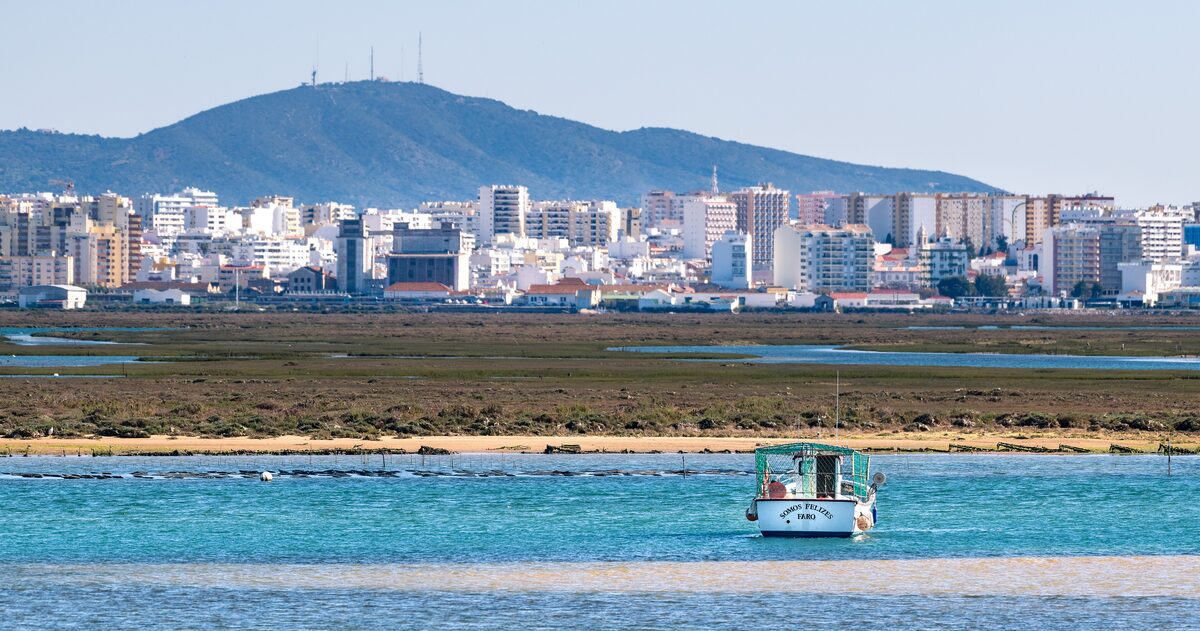 A boat on the Ria Formosa lagoon with the Faro skyline behind it