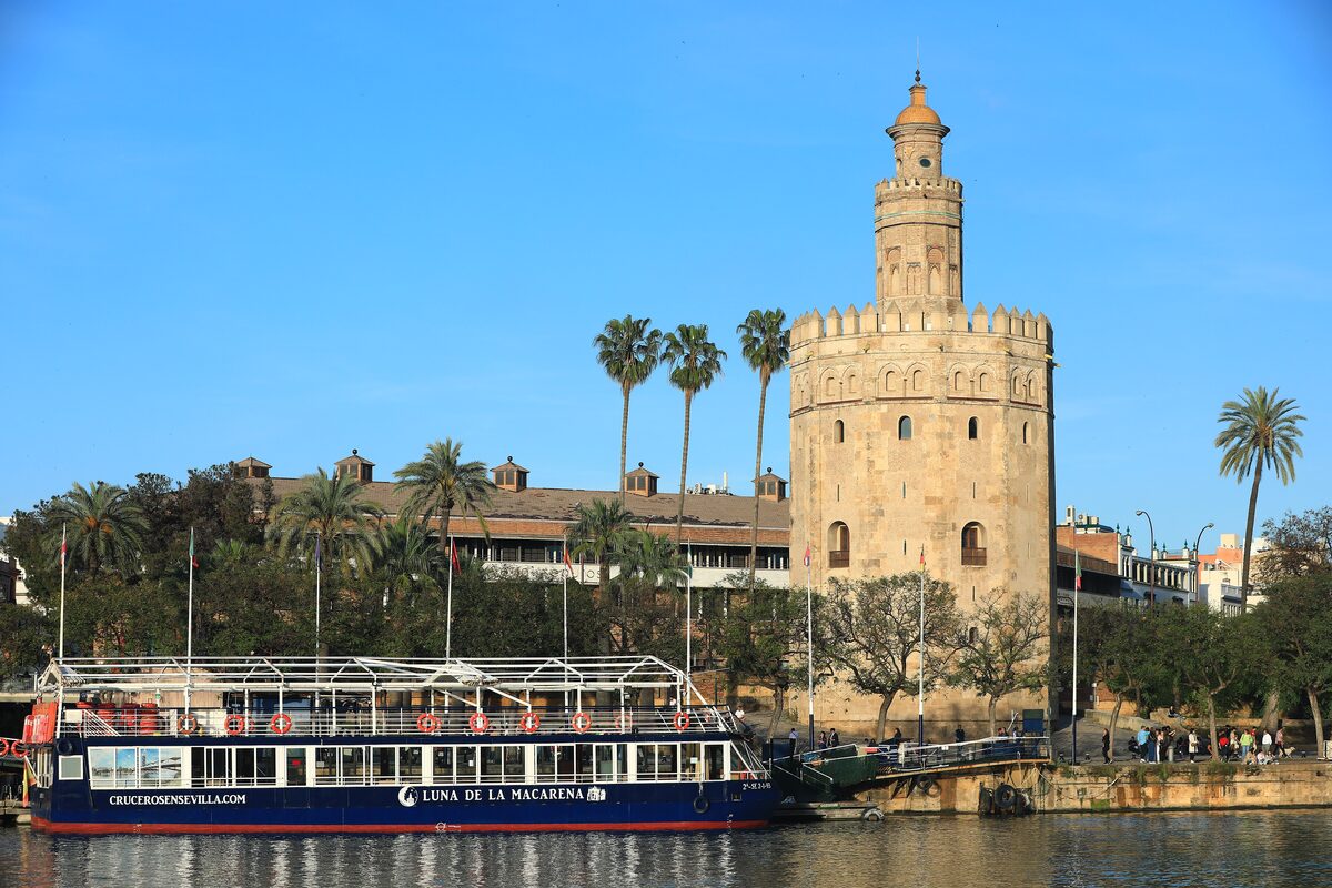 The Torre del Oro on the Guadalquivir river in Seville with a tour boat moored in front