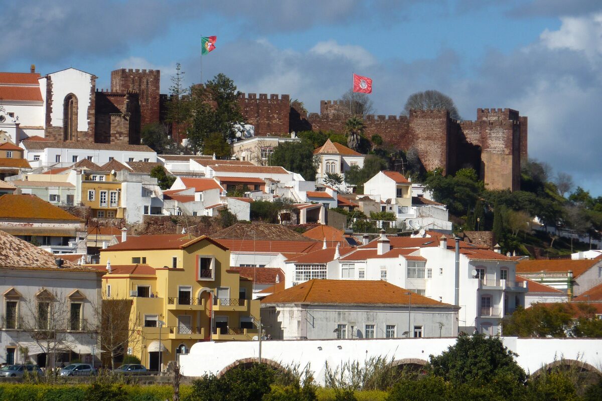 The red sandstone walls and towers of Silves castle above the white and terracotta houses of the town