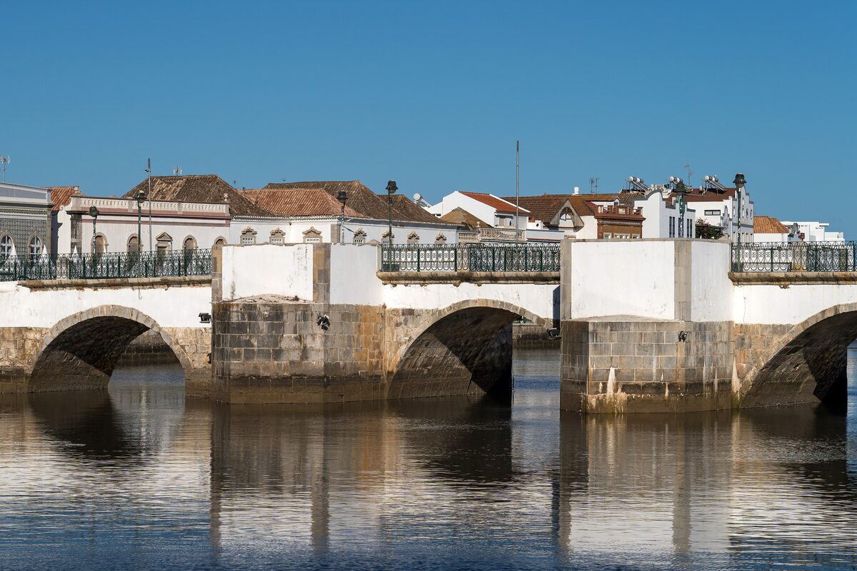 The arched old bridge over the Gilão river in Tavira with the town behind
