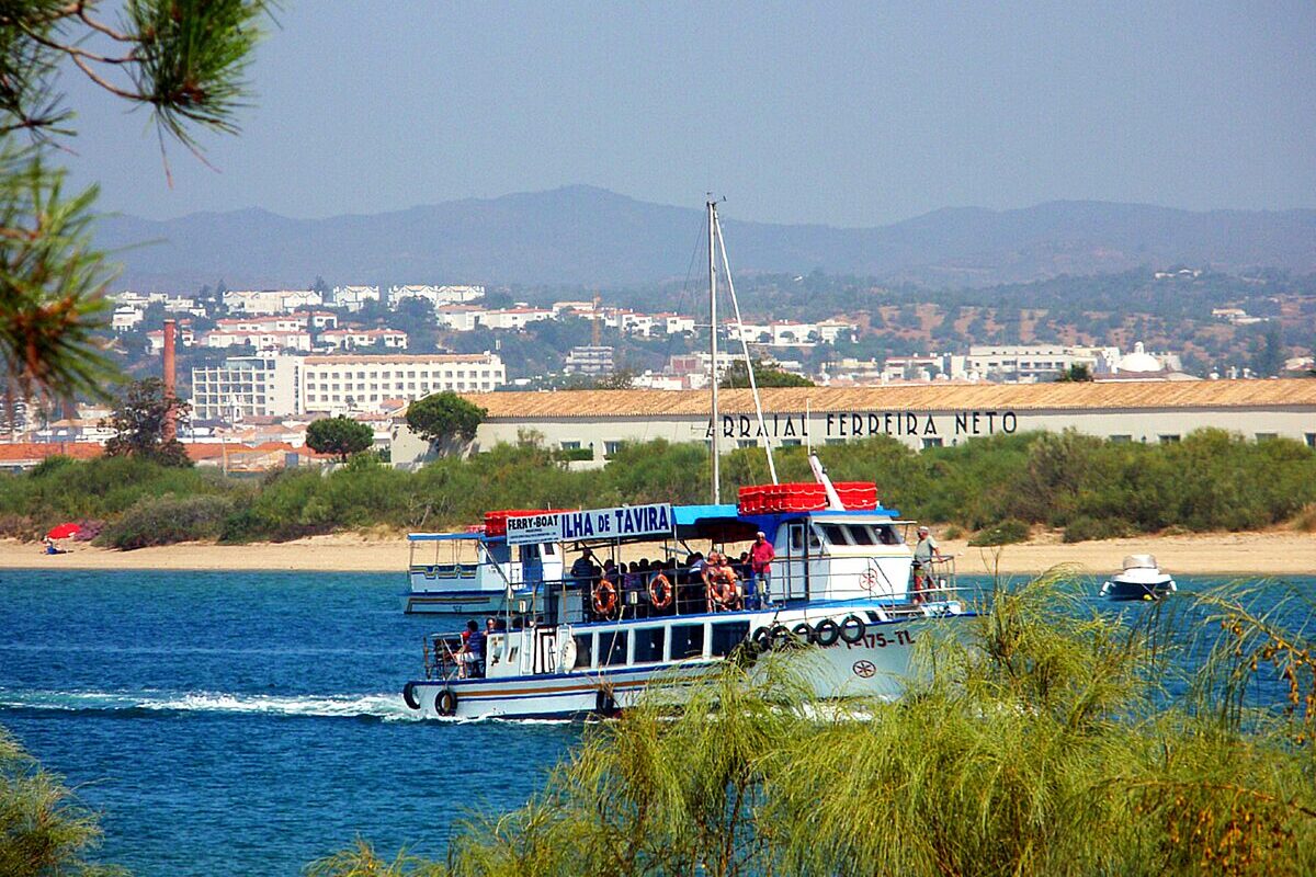The passenger ferry to Ilha de Tavira crossing the Ria Formosa, with the town of Tavira and hills behind