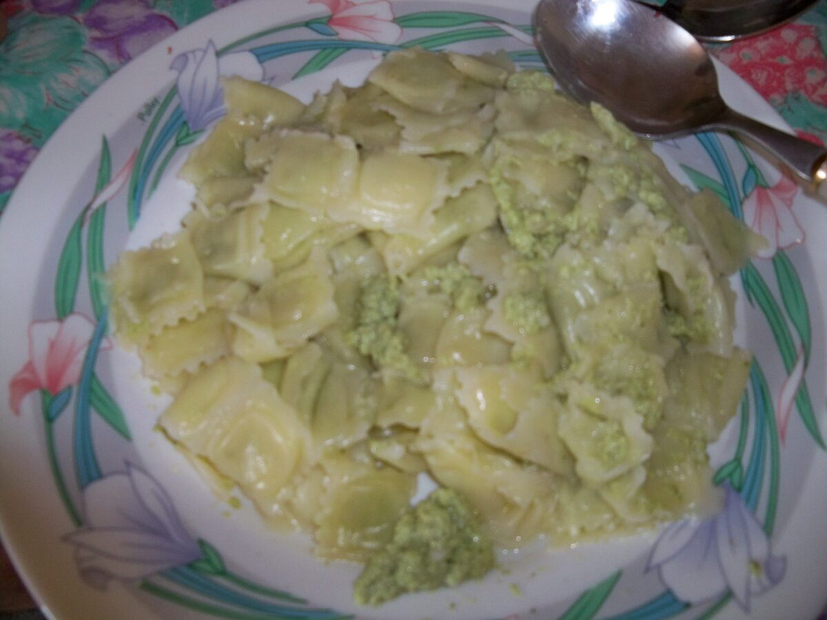 A plate of small cooked cheese ravioles with a green herb sauce