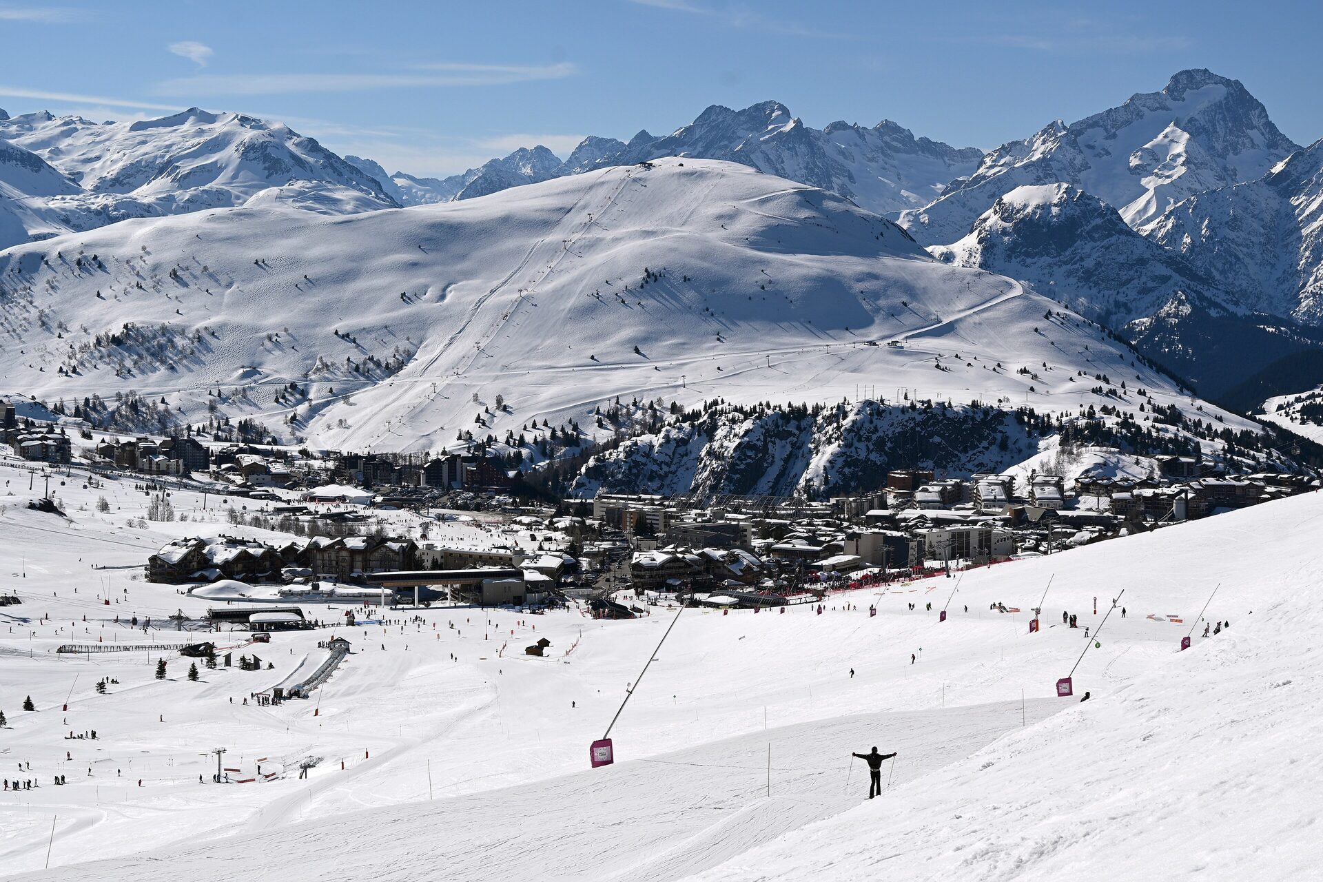 The village of Alpe d'Huez under snow, with its pistes and a lift station in front and the mountains behind