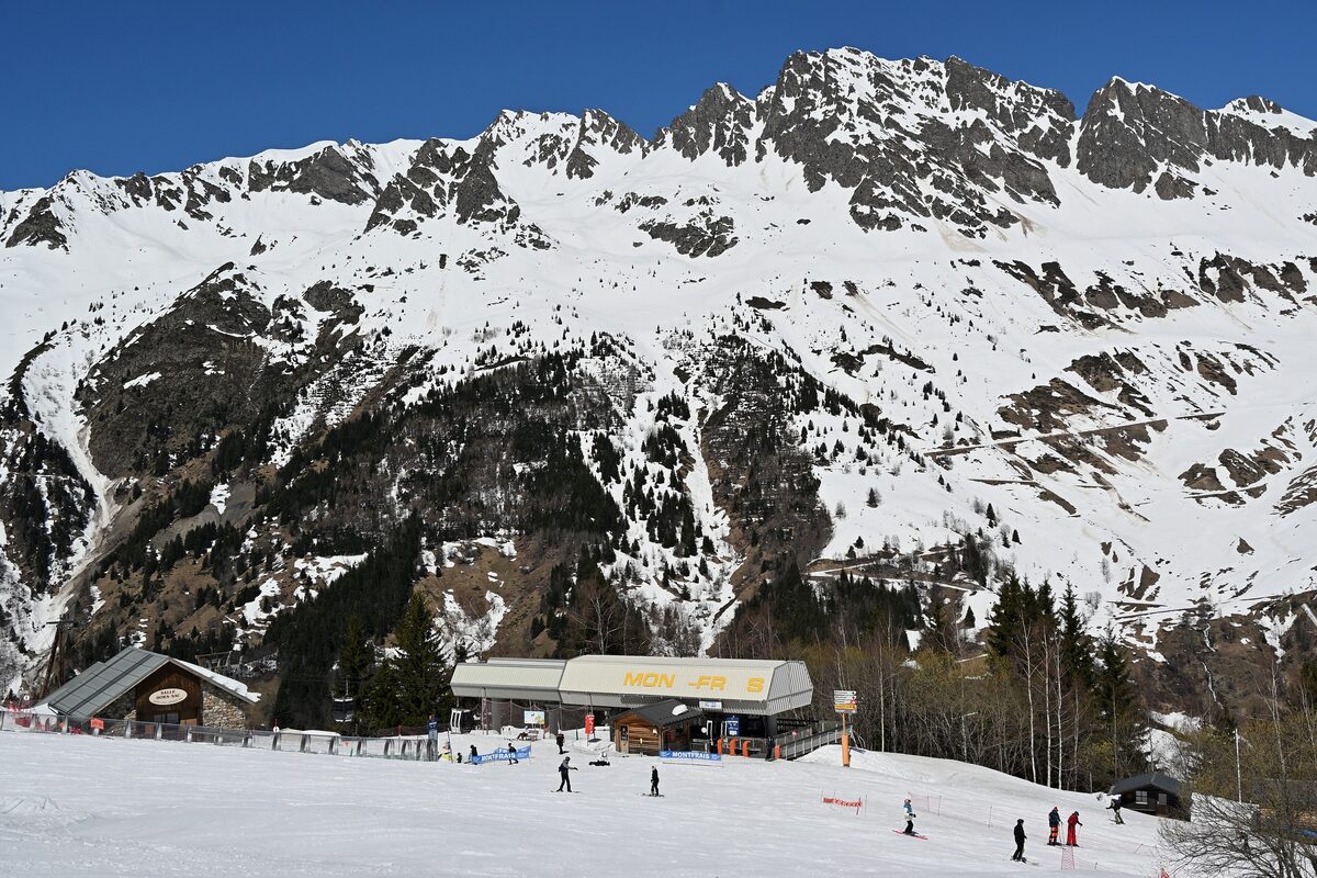 Skiers on the snowy Montfrais slopes beside the top station of the Montfrais gondola, under a clear sky