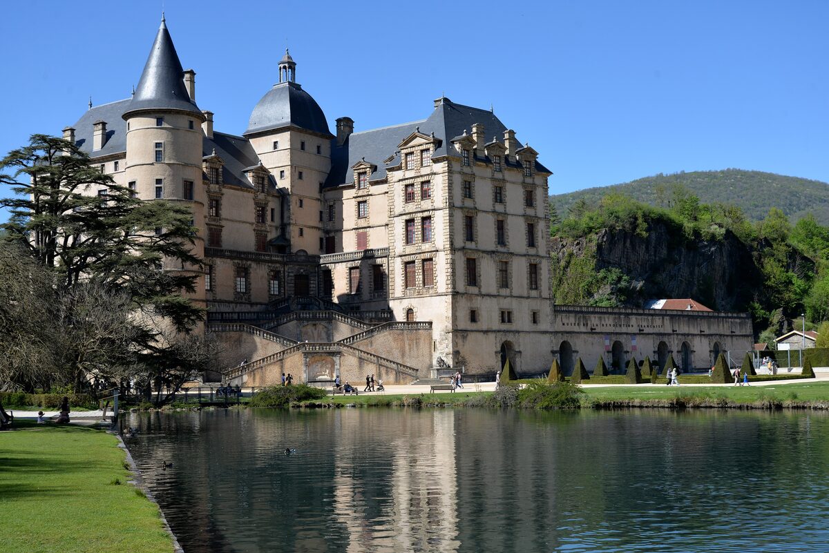 The Château de Vizille on a sunny spring day, a turreted château with its reflection in the pond in front