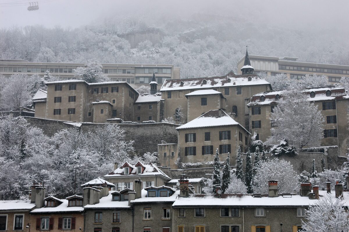 The Musée Dauphinois buildings on the slope above Grenoble, with snow on the roofs and the trees