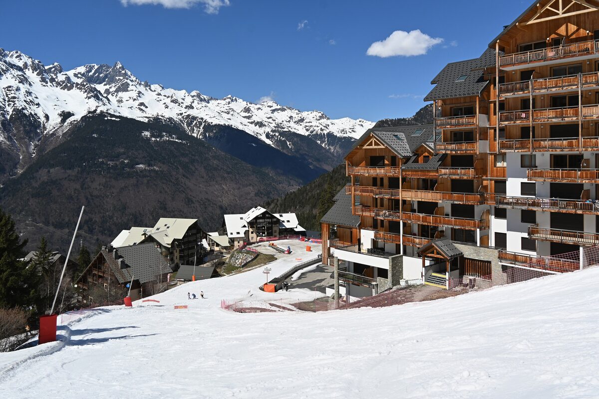 The Oz 3300 apartment buildings and chalets at the foot of the snowy pistes, with the mountains of the valley behind