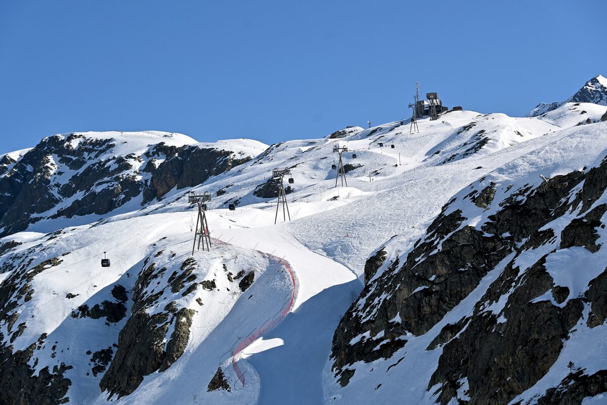 The Pic Blanc 2 cable car climbing the snowy ridge above the Grandes Rousses, with its pylons and the cabins in the air