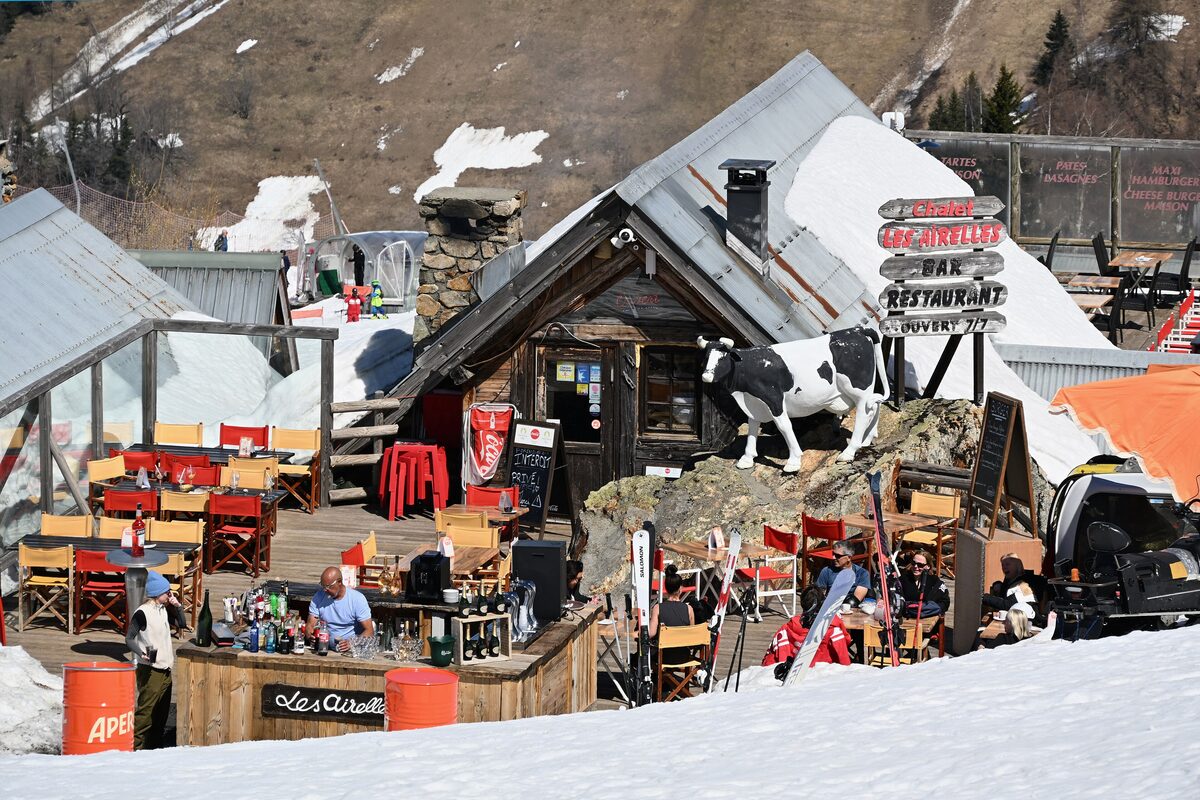 The Les Airelles mountain restaurant on the slopes above Vaujany, with diners at tables on the sunny terrace and skis stuck in the snow