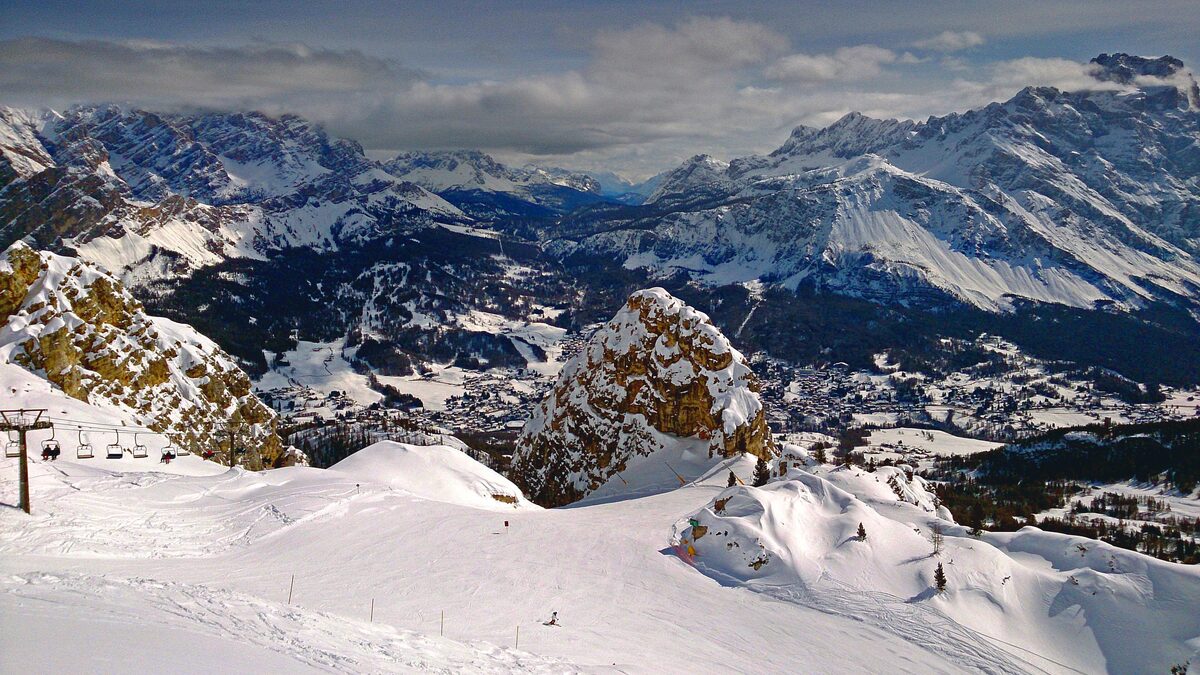 Cortina d'Ampezzo under snow, seen from the slopes above with the Dolomite peaks around the town