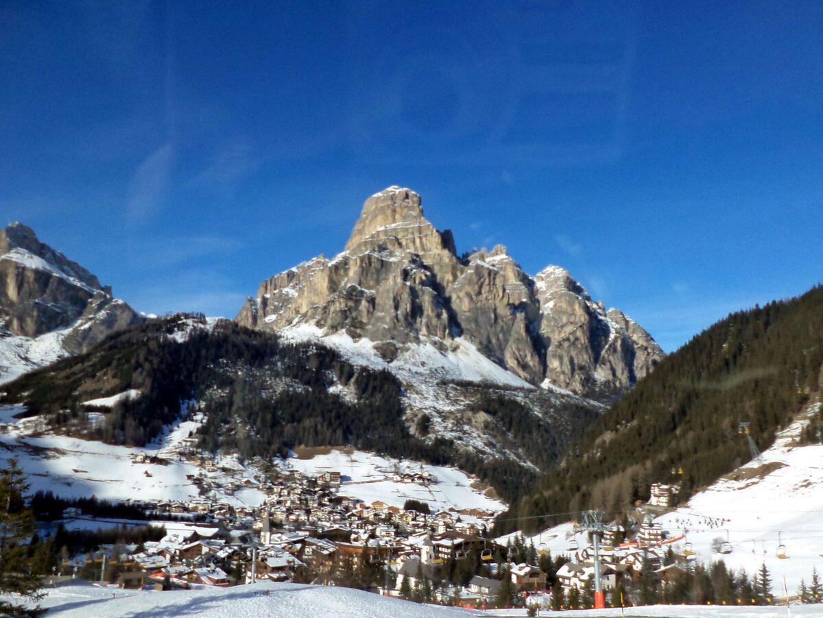 Corvara under snow, with the rocky peak of the Sassongher rising above the village roofs