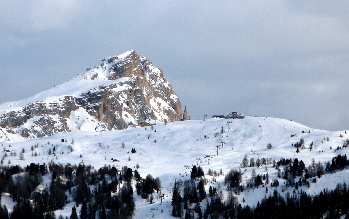 The Pralongià plateau under snow, with a rocky peak, groomed pistes and a lift station on a winter day