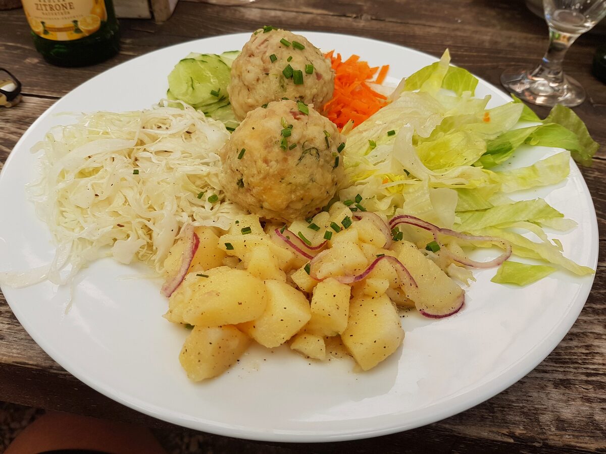 Speck dumplings with sauerkraut and a mixed salad on a plate